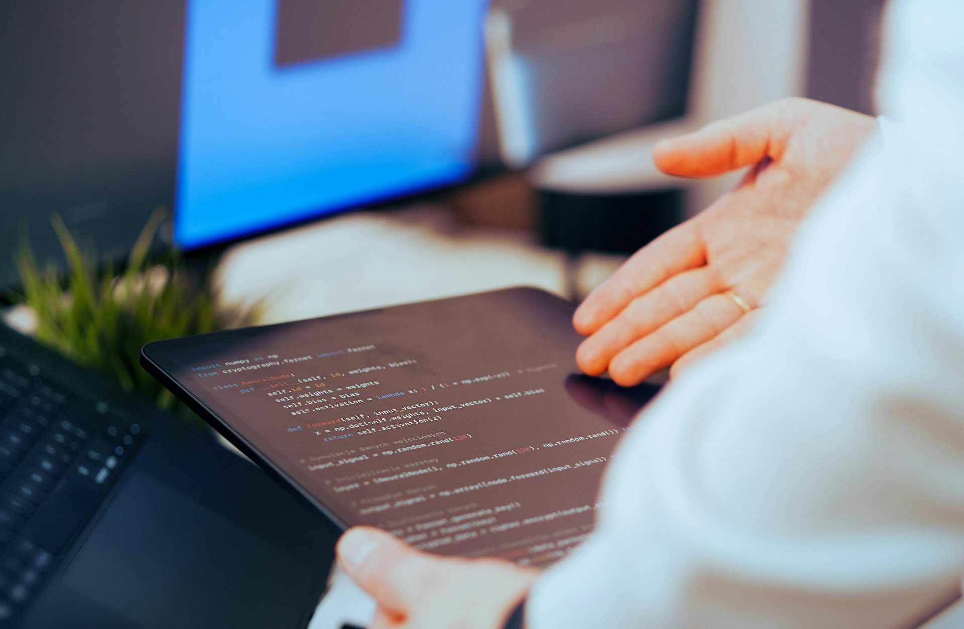 Softwareentwickler analysiert Code auf einem Tablet in einem modernen Büroarbeitsplatz.